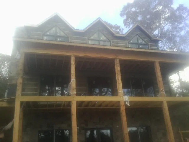Dormers and porch framing on a large log home under construction — Roof Coating work by our crew in Harveyville