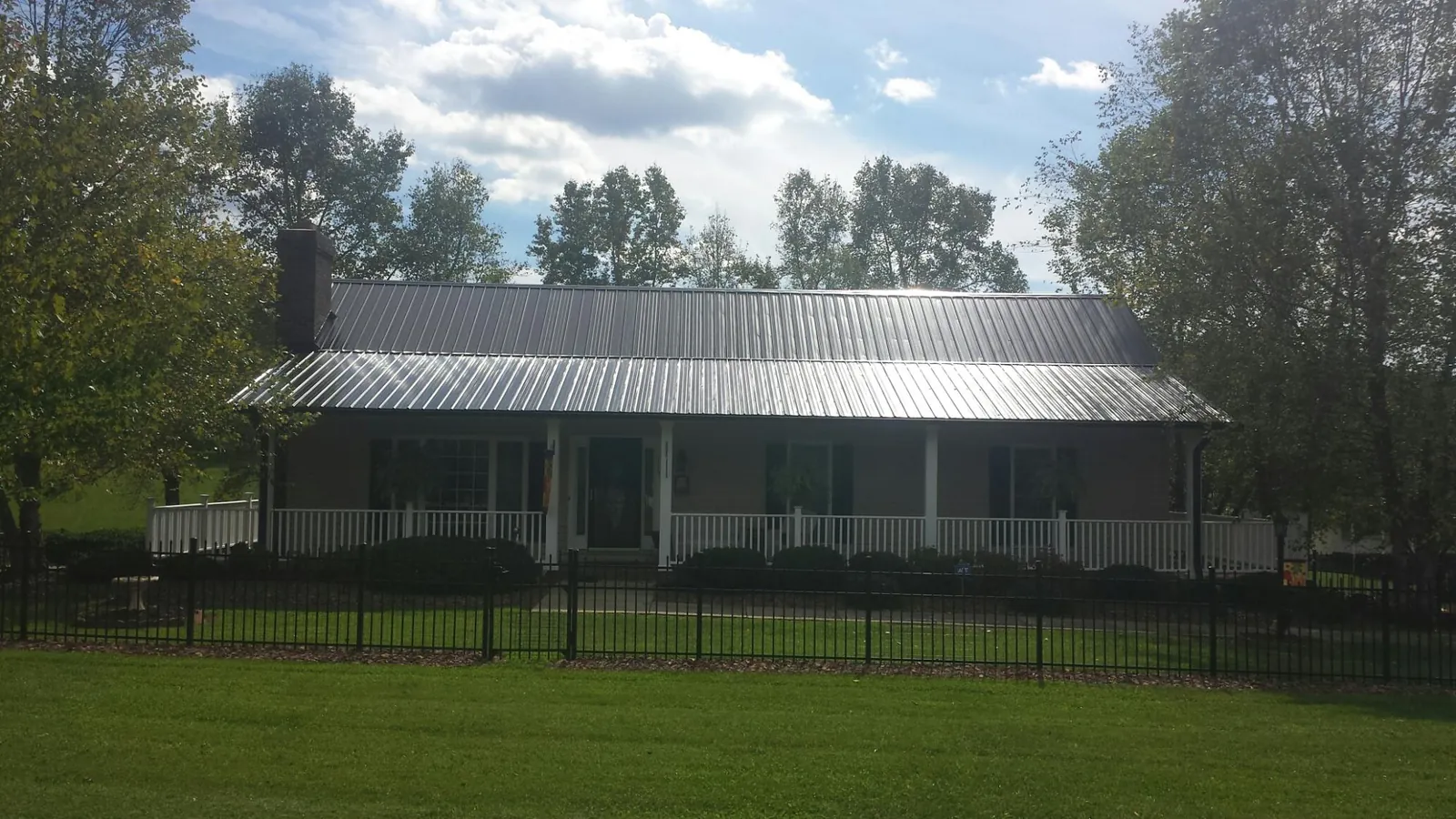 Gray metal roof on a brick ranch with a full width front porch — Gutter Guard Installation work by our crew in Harveyville
