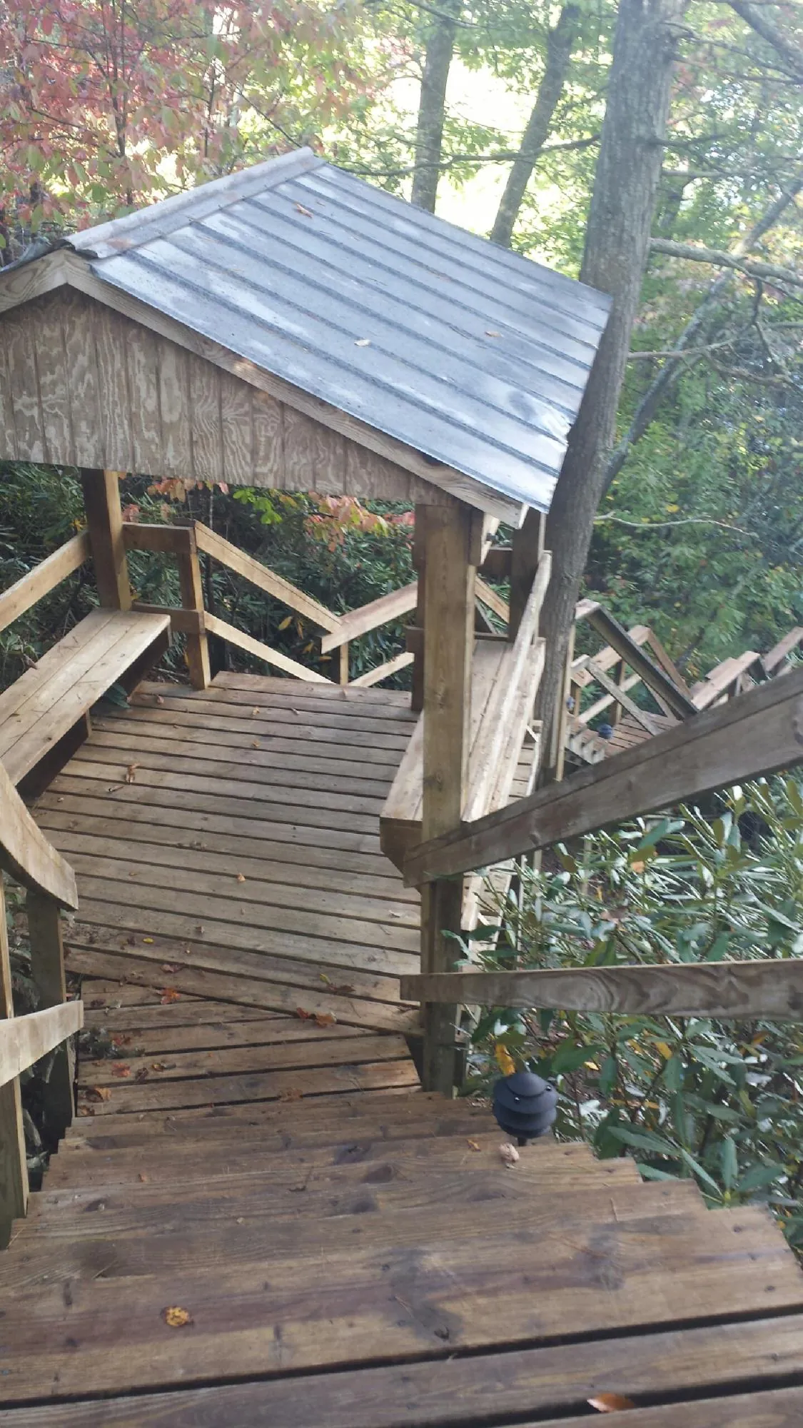 Metal roofed shelter over wooden steps on a wooded walkway — Skylight Repair & Installation work by our crew in Harveyville