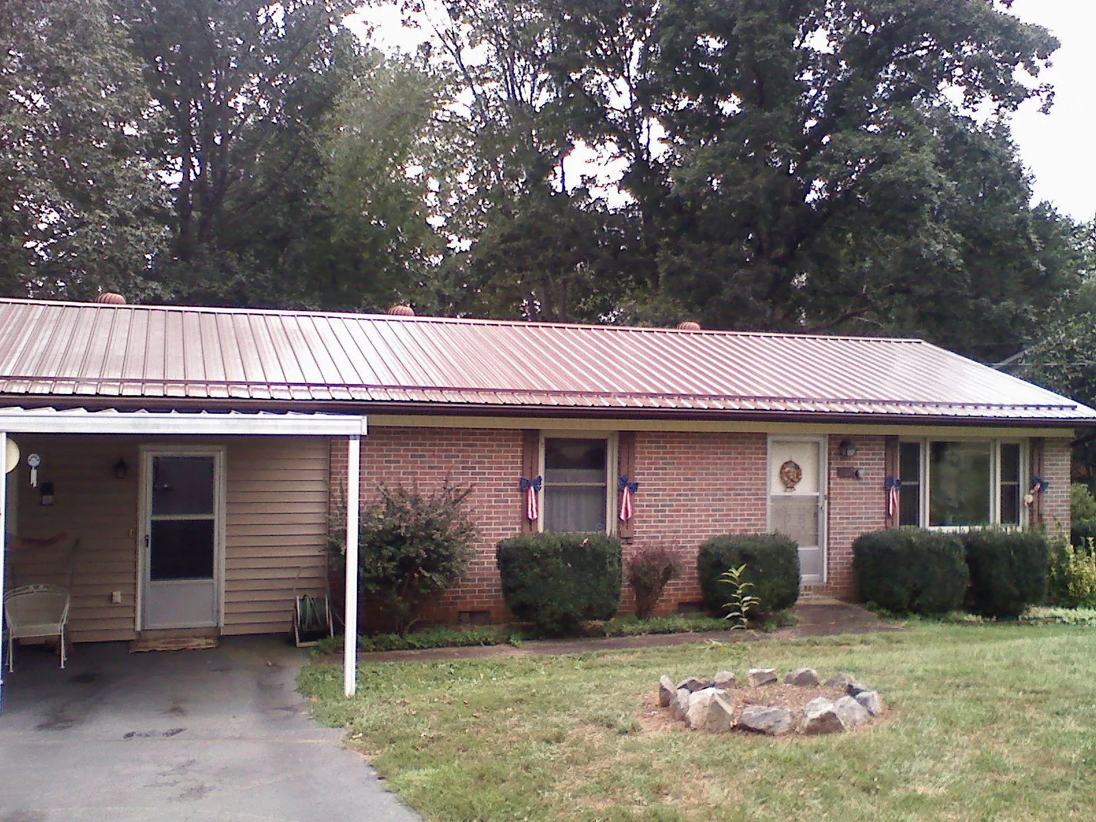 Bronze metal roof and carport on a brick ranch home — Roof Repair work by our crew in Harveyville