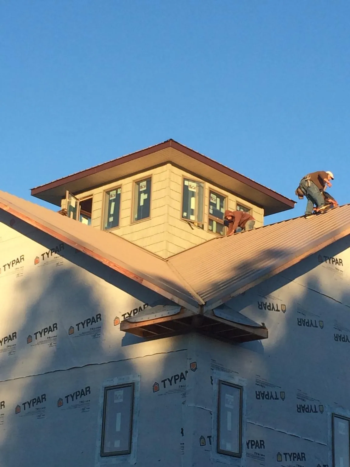 Roofers working around a rooftop cupola on a new metal roof at sunset — Roof Waterproofing in Harveyville by Roofing Brothers
